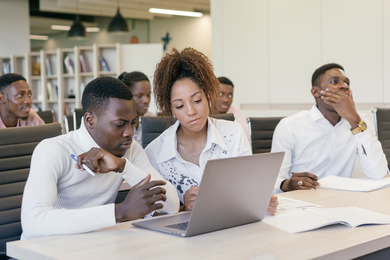 A diverse group of colleagues brainstorming together at a modern office setting with laptops.